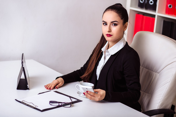 beautiful modern businesswoman in her office with a paper folder and tablet computer and mobile phone - Fotó, kép