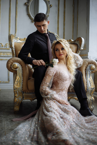 Gorgeous young woman with perfect makeup and hair style in luxury dress with a man in black clothes in interior - Fotoğraf, Görsel