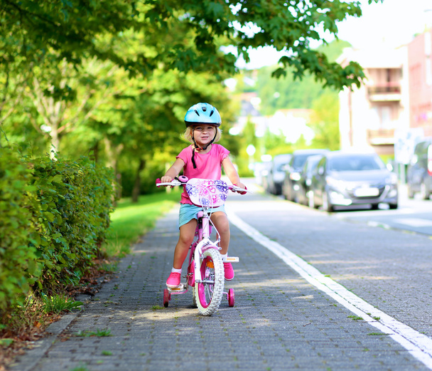 Toddler girl riding with her bike - Фото, изображение