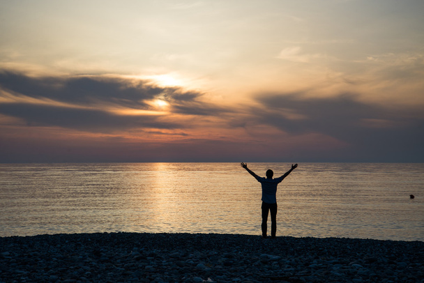 Silhouette de l'homme levant les mains ou les bras ouverts quand le soleil se lève
 - Photo, image