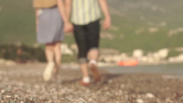 Rakastava pari kävelee pitkin rannikkoa kädestä pitäen ja suudellen hämärtynyt
 - Materiaali, video