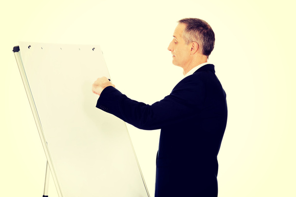 Male executive writing on a flipchart - Фото, изображение