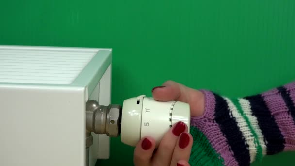 Vrouw Hand met handschoen aan te passen temperatuur van de thermostaat van de Radiator op groen. - Video