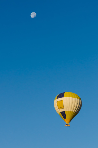 Balão de ar quente voando sobre céu azul claro com Lua
 - Foto, Imagem