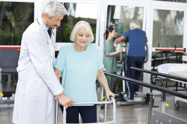 Ärztin hilft Seniorin mit Rollator im Fitnessstudio - Foto, Bild