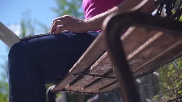 Man sitting on a bench with a laptop, and then will go outdoors - Záběry, video