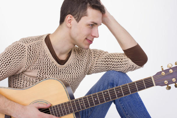 guitarist young guy in jeans with a guitar sitting  - Foto, imagen