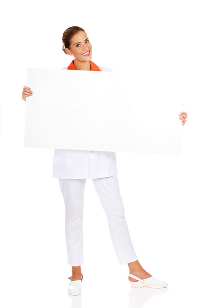 Happy female doctor or nurse holding empty banner - Φωτογραφία, εικόνα