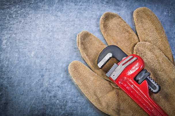 Pipe wrench safety gloves on scratched metallic background - Foto, Imagem