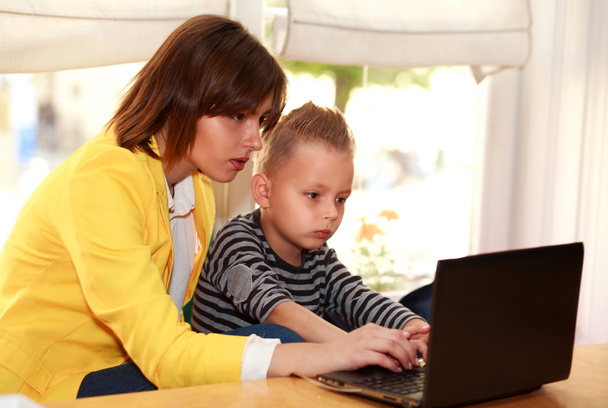Mother and son at home doing lessons looking at laptop - Foto, Imagen