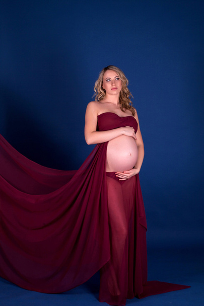 zwanger vrouw in rode jurk - Foto, afbeelding