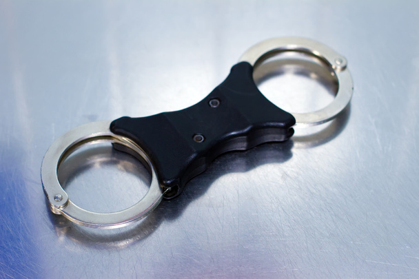 Police style handcuffs on a shiny silver backdrop - Photo, Image