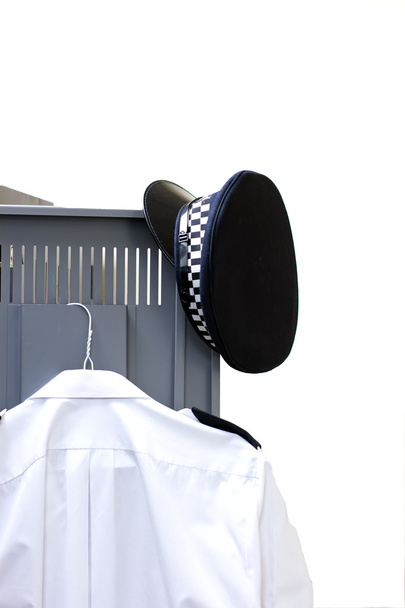 policemans καπέλο και πουκάμισο κρέμεται σε μια πόρτα ντουλαπιών - Φωτογραφία, εικόνα