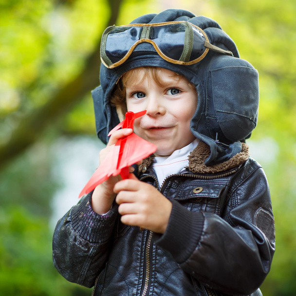 Little kid boy in pilot helmet playing with toy airplane - Photo, image