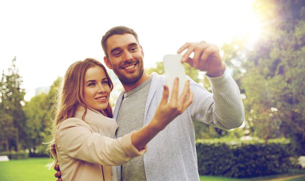happy couple with smartphone taking selfie in park - Zdjęcie, obraz
