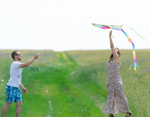 pareja amorosa están lanzando cometa en un prado
 - Foto, Imagen
