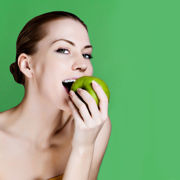 Woman eating apple smiling on green background. Healthy eating candid woman. - Foto, Bild