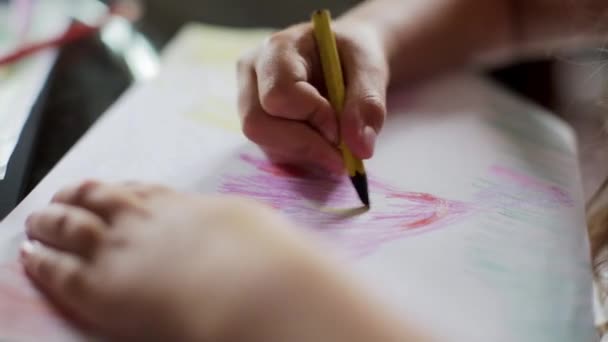 little girl draws with crayons sitting at table. close up - Záběry, video