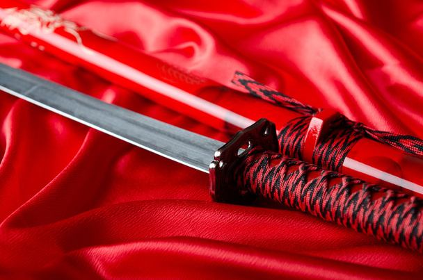 A japán kard takana piros szatén háttér - Fotó, kép