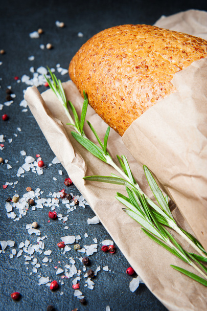 Hoja de pan con sal de romero y pimienta sobre papel
 - Foto, Imagen