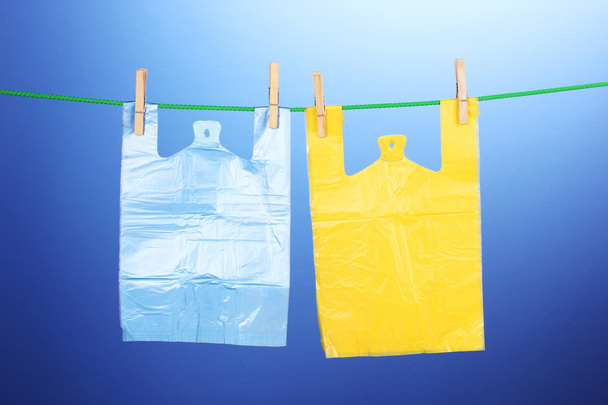 Cellophane bags hanging on rope on blue background - Foto, Imagem