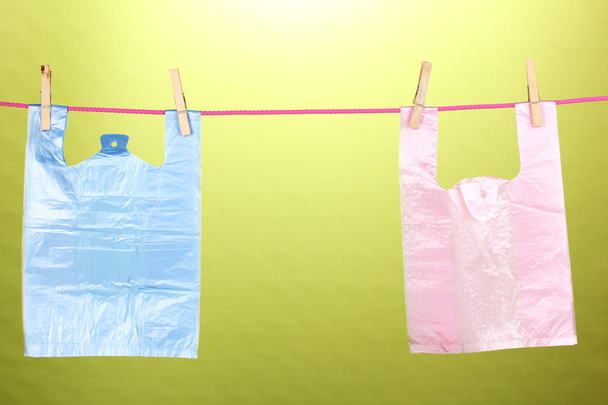 Cellophane bags hanging on rope on green background - Foto, Bild