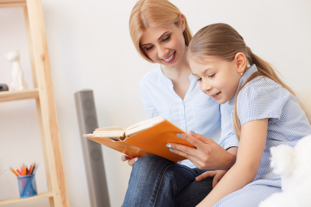 Mother and daughter reading book at home - Foto, imagen