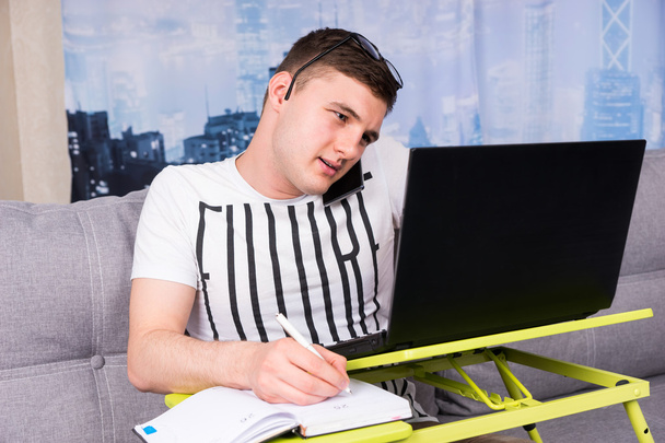 Oszołomiony przystojny młody mężczyzna pracujący na laptopie  - Zdjęcie, obraz