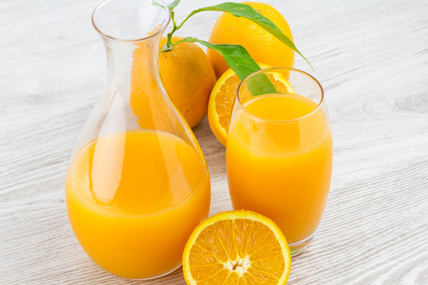 Апельсины и стакан сока на деревянном столе
 - Фото, изображение