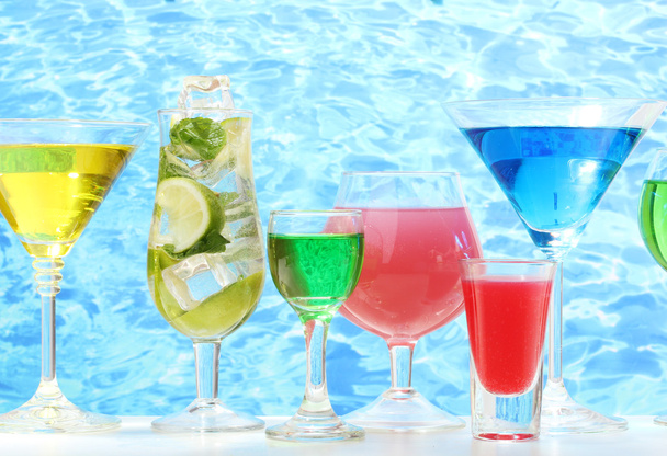 Glasses of cocktails on table on blue sea background - Fotoğraf, Görsel