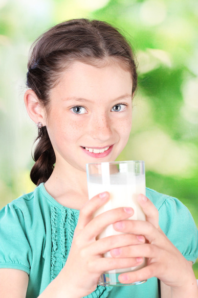 Portrait of beautiful little girl withglass of milk on green background - Photo, image