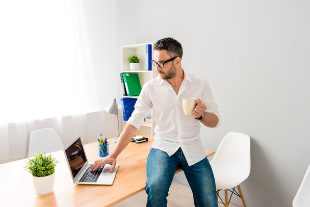 Smart biznesmen pracę z laptopem i picia kawy - Zdjęcie, obraz