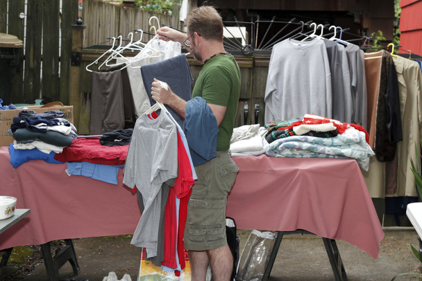 Человек, держащий одежду в продаже
 - Фото, изображение