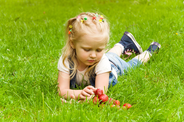 meisje, eten van een aardbei in de natuur - Foto, afbeelding