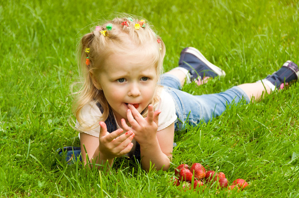 little girl eating a strawberry in nature - Photo, Image