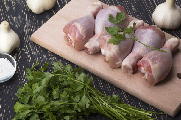 raw chicken drumstick on the board with salt, garlic, parsley - Photo, Image