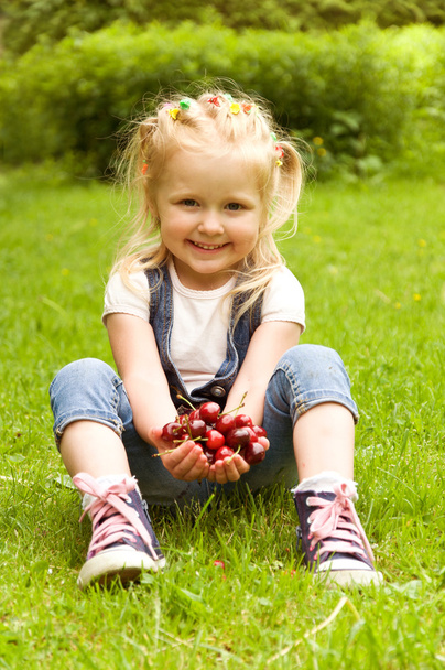 niña comiendo una cereza en la naturaleza
 - Foto, Imagen