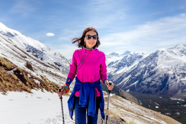 Wandelaar vrouw lopen op hoogteweg met stokken, wandelen, kijken naar weergave Elbrus regio, Kaukasus - Foto, afbeelding