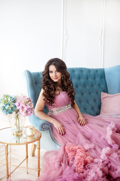 青い椅子に座っているピンクのドレスで幸せな妊娠中の女性。ファッション撮影 - 写真・画像