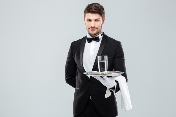 Butler in gloves holding glass of water on silver tray - Foto, Imagem
