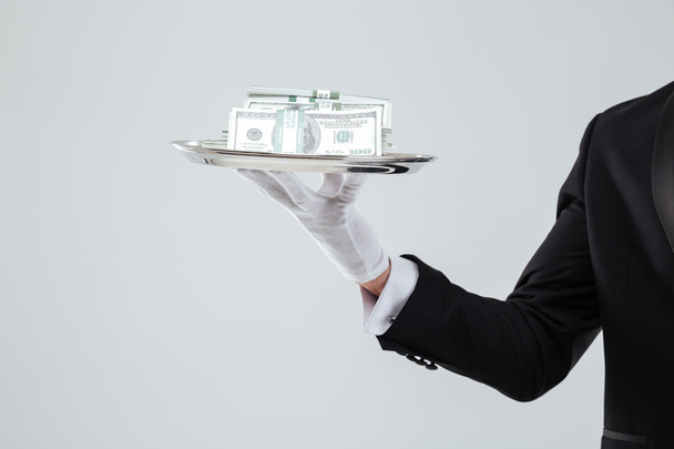 Tray with money holded by waiter hand in glove - Foto, Imagen