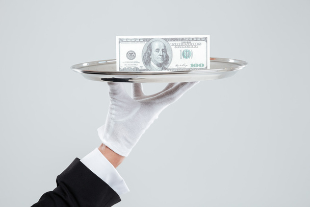 Hand of waiter in white glove holding tray with dollars - Zdjęcie, obraz