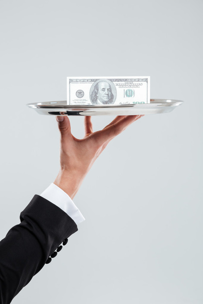 Hand of waiter in suit holding tray with money - Fotoğraf, Görsel