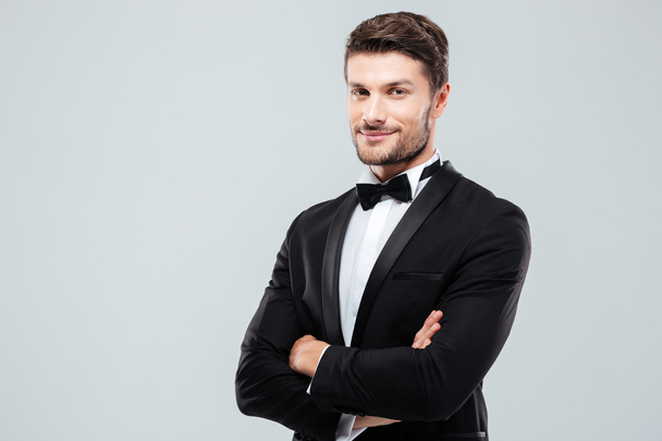 Smiling confident man in tuxedo standing with arms crossed - Fotó, kép