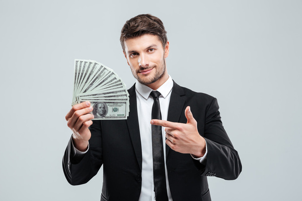 Attractive young businessman holding money and pointing on it - 写真・画像