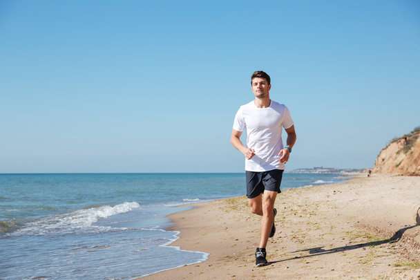 Happy sportsman running on the beach - Valokuva, kuva