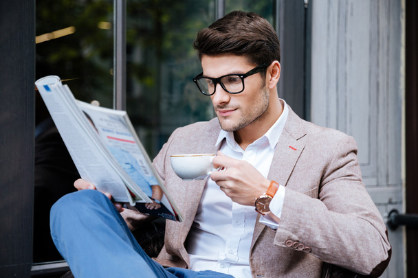 Concentrated man with coffee and magazine sitting in outdoor cafe - Foto, immagini