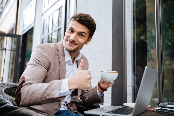 Empresário segurando xícara de café e trabalhando com laptop ao ar livre
 - Foto, Imagem