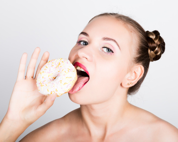 girl in bright makeup eating a tasty donut with icing. Funny joyful woman with sweets, dessert. dieting concept. junk food - Photo, Image