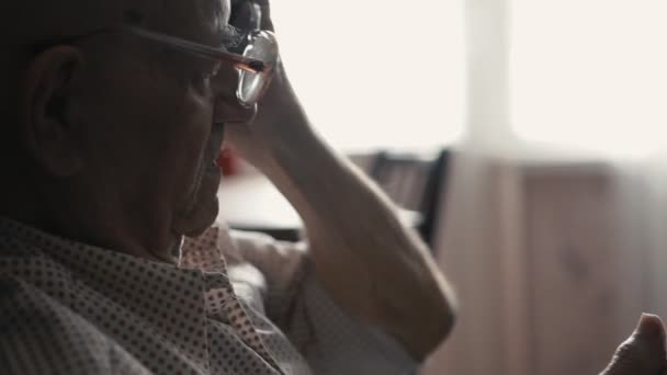 portrait of old man dressing glasses and using a smartphone at home, close up - Footage, Video